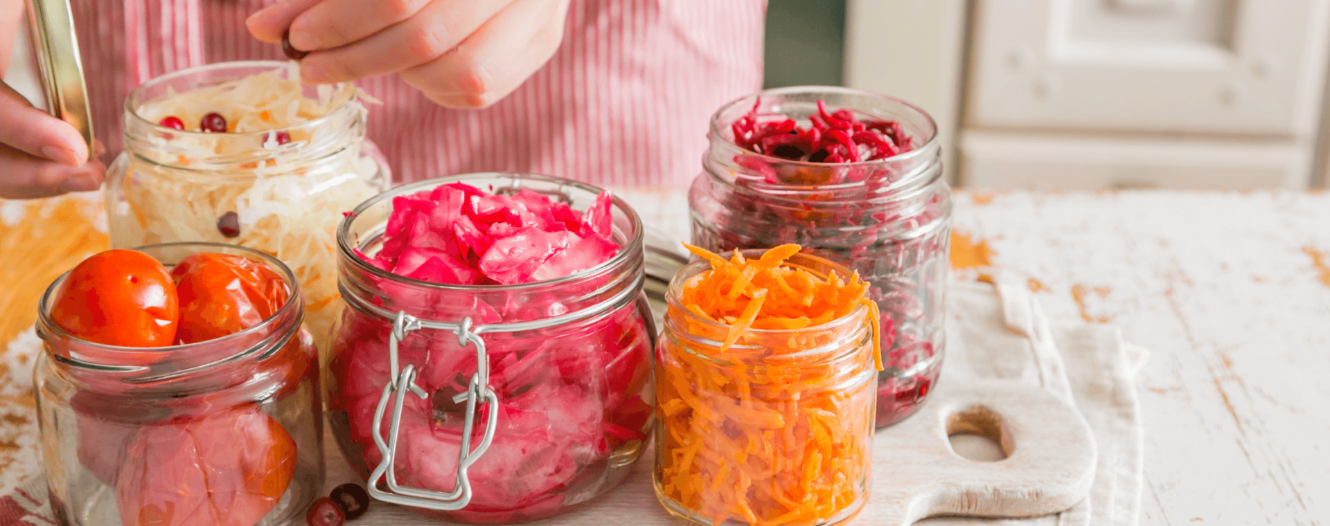 jars containing colorful vegetables are arranged on a counter