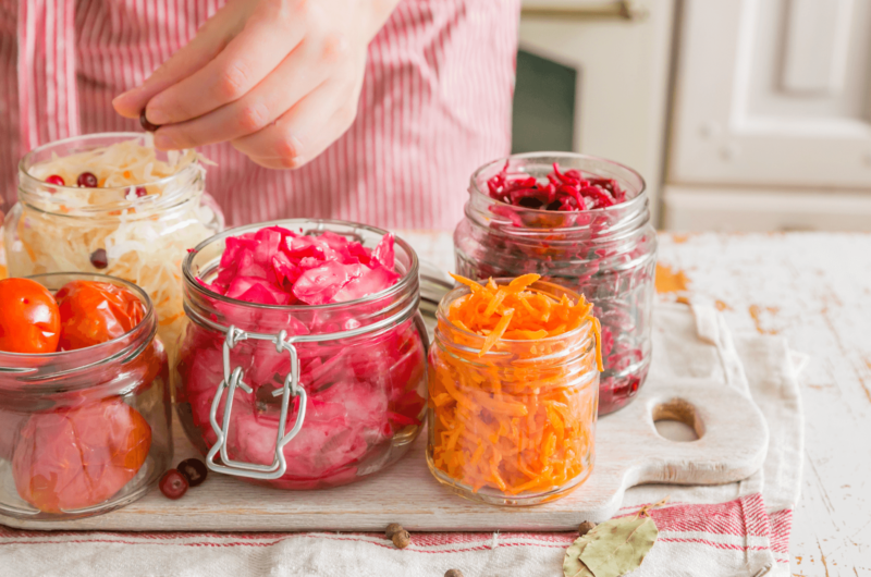 jars containing colorful vegetables are arranged on a counter