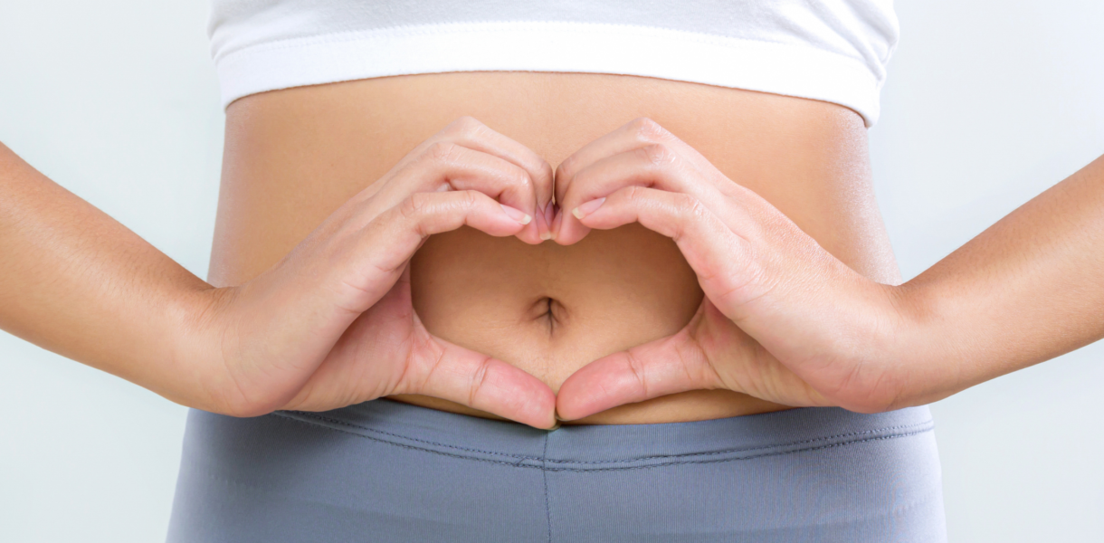 a person holds their hands in the shape of a heart over their navel