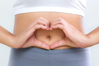 a person holds their hands in the shape of a heart over their navel