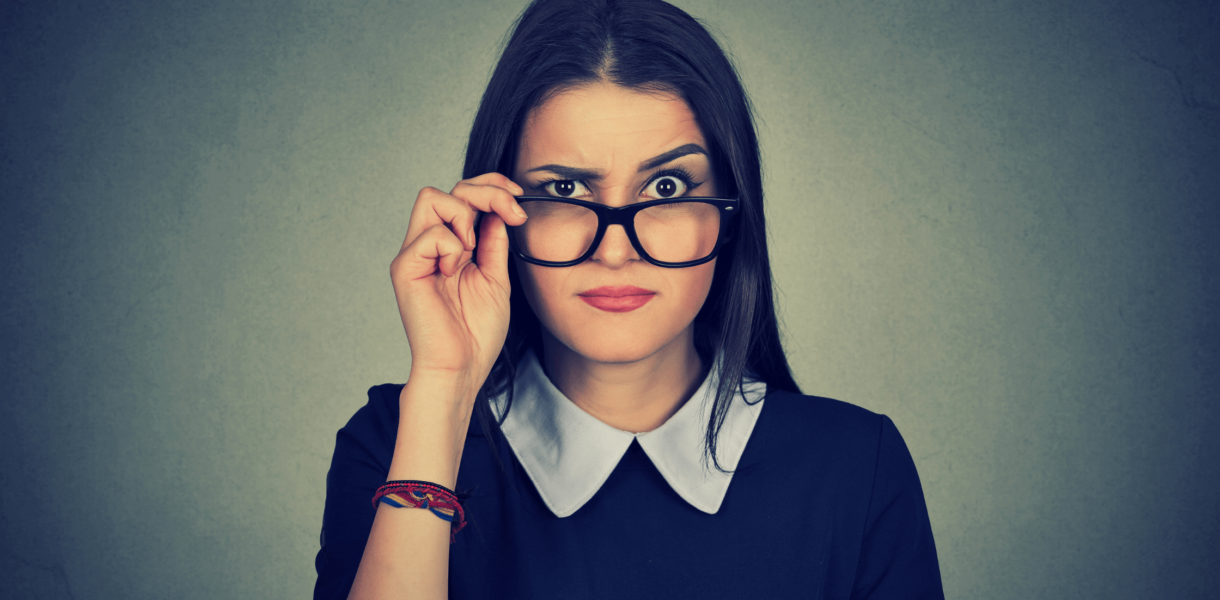 a woman is pulling her glasses down and raising an eyebrow