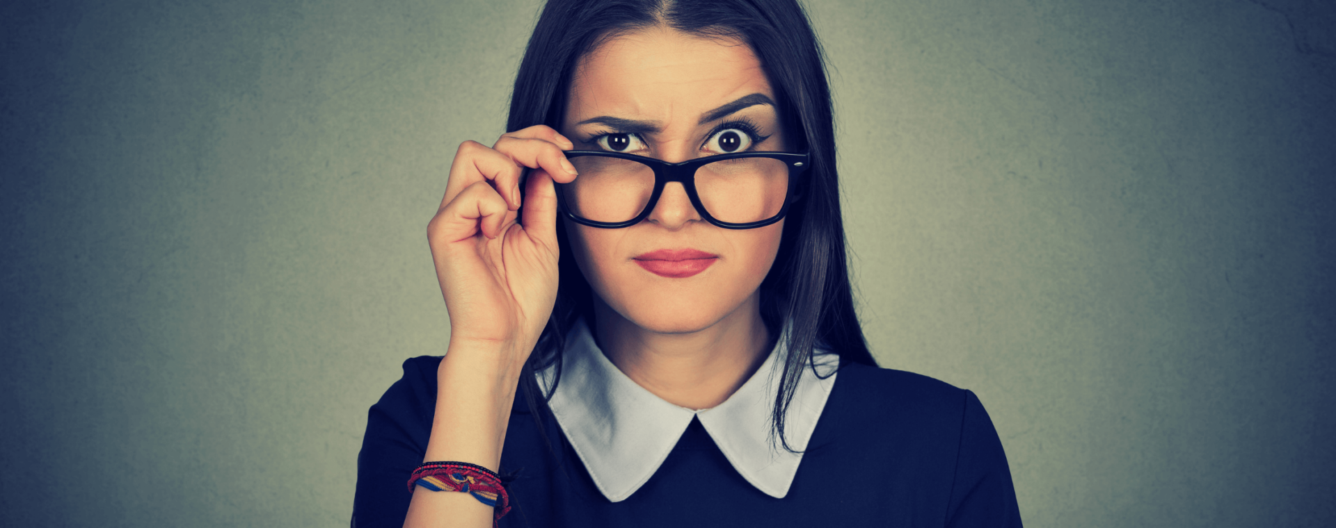 a woman is pulling her glasses down and raising an eyebrow