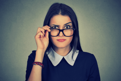 a woman is pulling her glasses down and raising an eyebrow